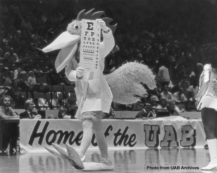A rooster mascot shows an eye chart to the crowd at a basketball game