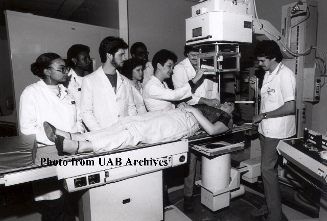 Students look on as a patient is under a radiology machine