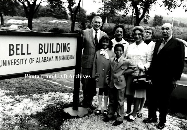 Dr. Volker and the Bell family stand next to the Bell Building sign