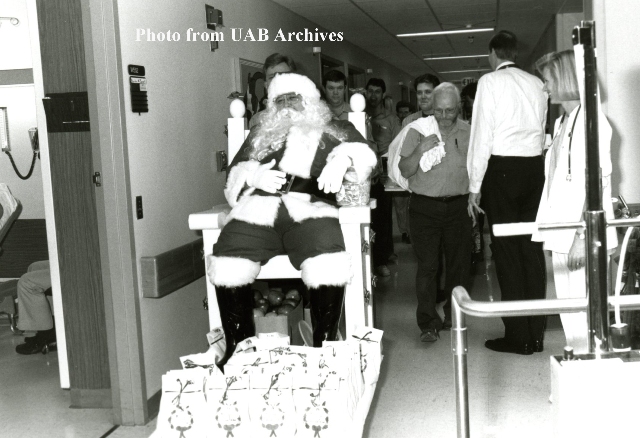 Santa riding on a chair through the hospital hallways