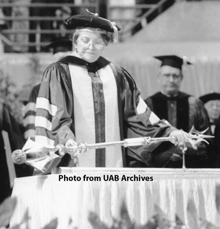 A woman holds a mace at a graduation ceremony