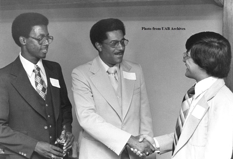 Aaron L. Lamar, Jr. shakes hands with a student while another student looks on