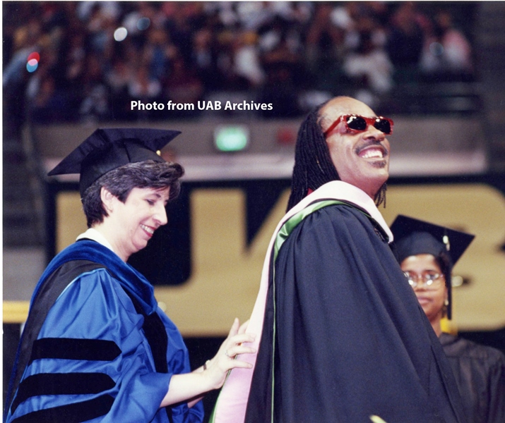 Dr. Lorden fixes a graduation hood on Stevie Wonder