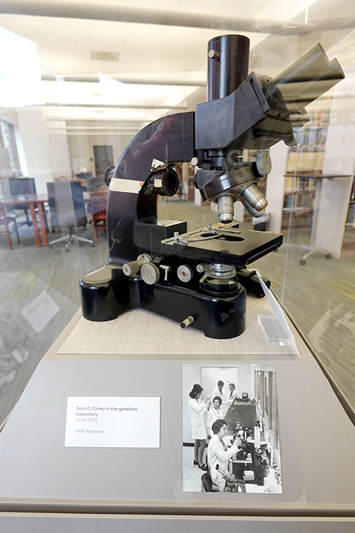 Museum case displaying a microscope from UAB Historical Collections.