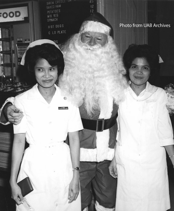 Two female nurses pose with Santa Claus