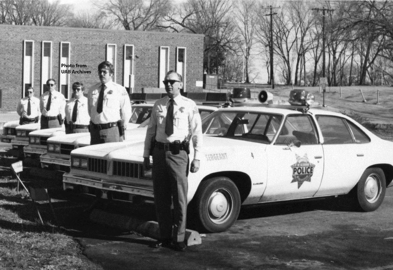 Police officers stand next to their cars
